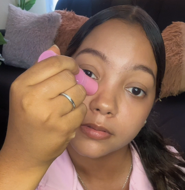 Applying the PDRN Pink Collagen Multi Volume Balm stick to the cheek with one hand